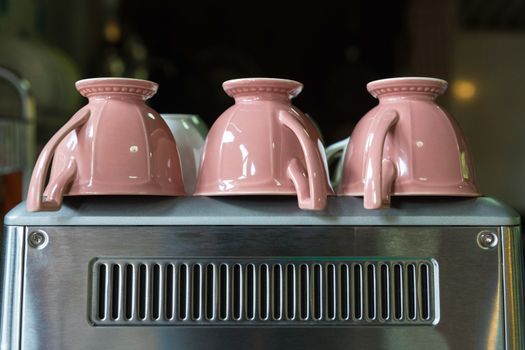 Three pink coffee cups upside down on Coffee maker.