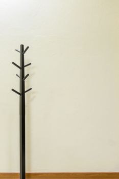 Black wooden coat rack on wall background, space for input text.