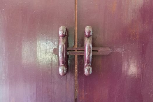 Old style wooden latch in red-purple color.