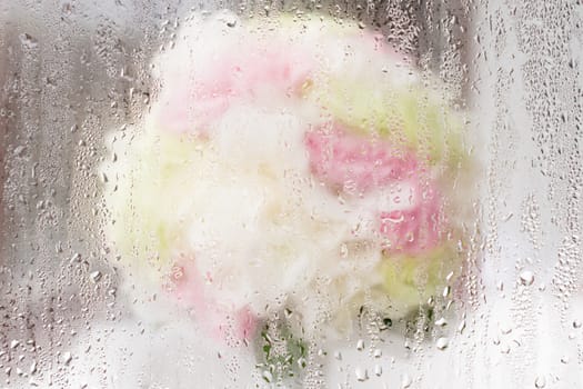 Blurry bouquet of roses behind water droplet mirror.