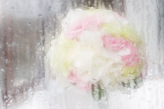 Soft focus bouquet of roses behind water droplet mirror.