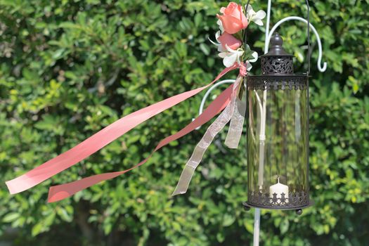 A decorated black cylinder lantern, floral and ribbon in wedding.