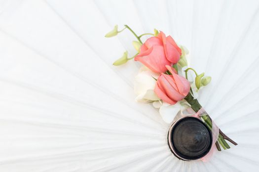 Bouquet of roses for groom and groomsman on white umbrella.