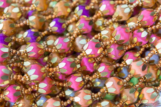 Indian traditional culture stuff from colourful beads pink violiet orange gold for holy religious ritual. Useful for background.