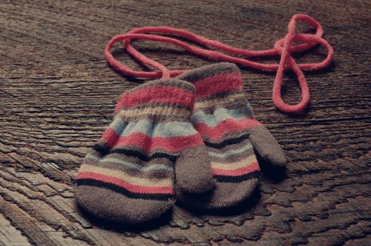 two knitted striped baby mittens on wood background