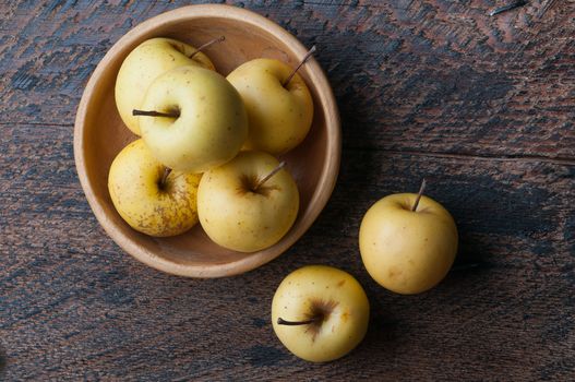 a few green apples in a wooden bowl on the table