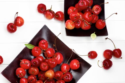 Two Black Wooden Plates with Fresh Ripe Sweet Maraschino Cherries closeup on Plank White background. Top View