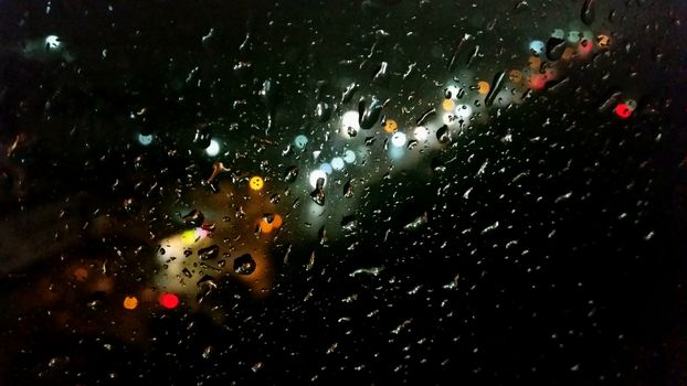 Raindrop on the window with street light bokeh in the raining night