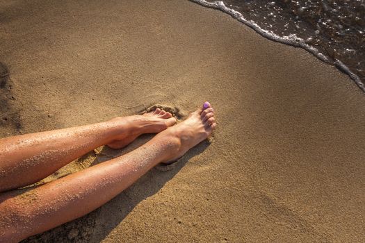 Women's sexy legs on the yellow sand beach