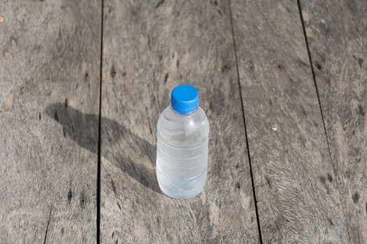 Plastic water bottle on wooden table texture. Fresh concept.