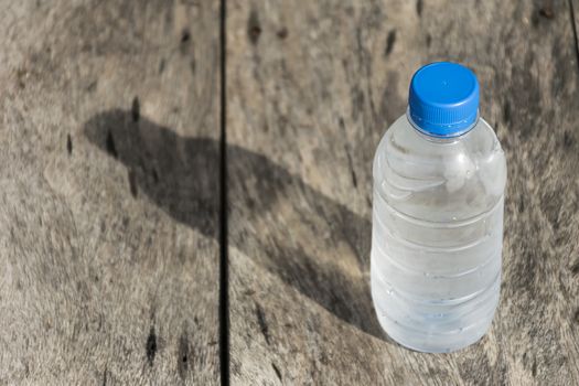 Plastic water bottle on wooden table texture. Fresh concept.