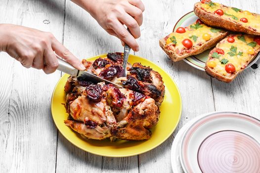 Hands with knife and fork,cutting up baked chicken