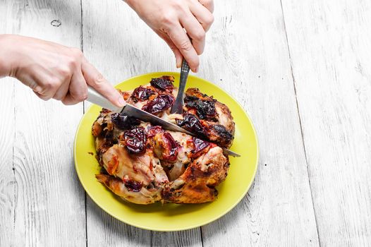 Hands with knife and fork,cutting up baked chicken