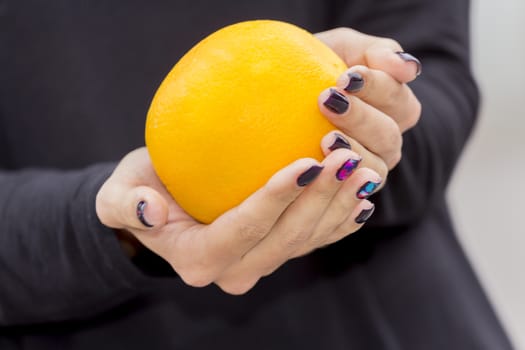 In the hands of a girl with a stylish manicure Orange bright orange