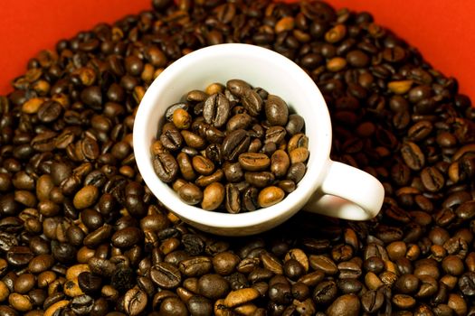 A coffee cup full of beans in a red background