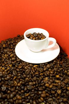 A coffee cup full of beans in a red background