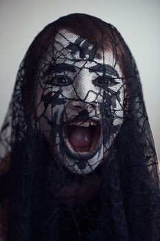 Portrait of a spooky girl screaming behind the veil