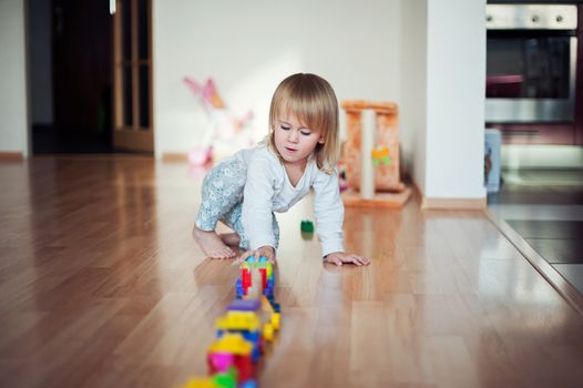 Little girl playing with train. Toddler kid play with trains and cars. Educational toys for preschool and kindergarten child. Girl build toy railroad at home or daycare.
