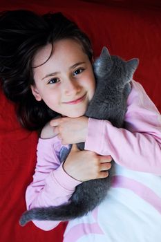 Happy little girl holding her gray kitten 