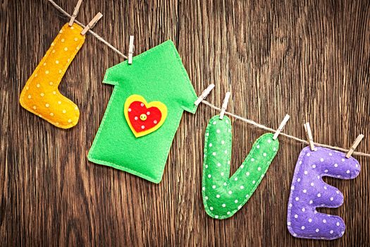 Love, Valentines Day. Word Love polka dots, house Handmade, hanging on rope. Retro vintage romantic style. Concept on wooden background, toned. Vivid greeting card, unusual creative, multicolored felt
