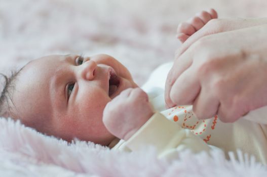 Smiling baby and woman hands wearing him