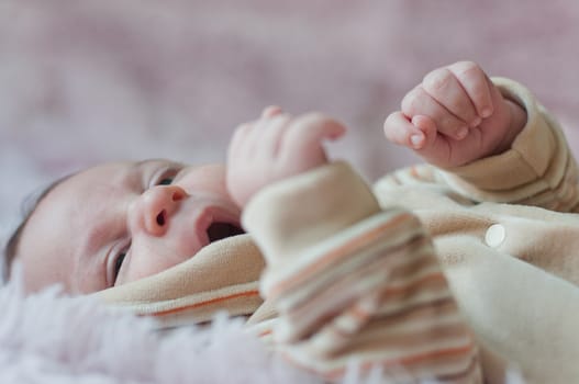 Little baby yawns and gets his hands  up