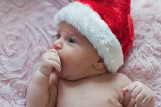 Little baby in santa christmas hat lays