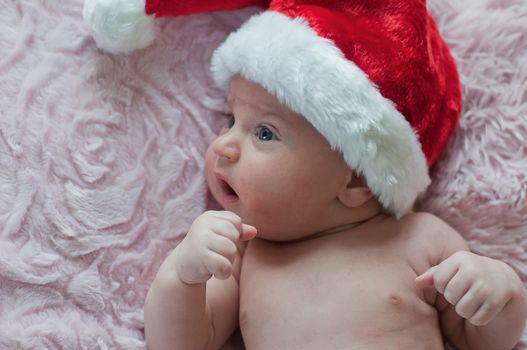Little baby in santa christmas hat lays