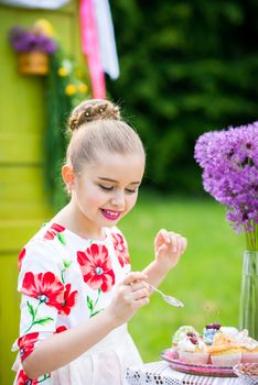 Little girl decorating cupcakes in in the backyard