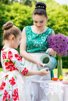 Young mother and her daughter cooking cupcakes together in the backyard