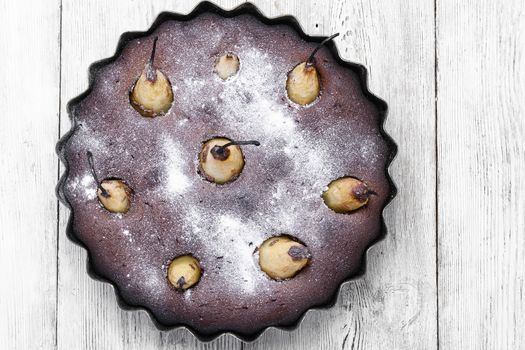 Autumn chocolate cake with whole pears on light background