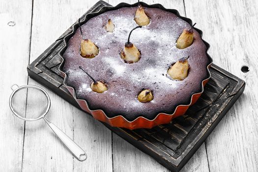 Autumn chocolate cake with whole pears on light background