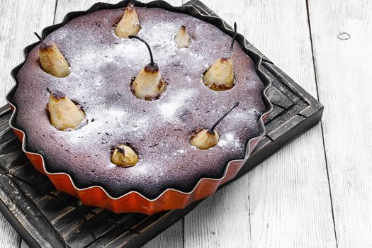 Autumn chocolate cake with whole pears on light background