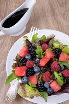 Fruit salad with blackberry, raspberry, blueberry, watermelon slices and mix of green leaves