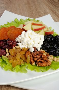 Vitamin salad with nuts, apples, dried fruit and cottage cheese in lettuce leaves