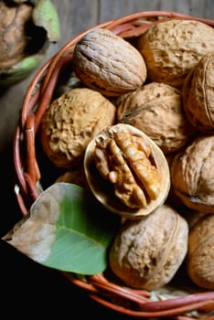 Walnut in basket and whole walnuts on rustic old wood