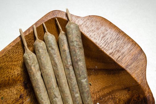 stock of hand made marijuana joints on wooden platter ashtray