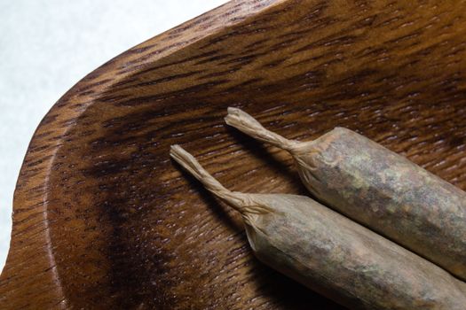 stock of hand made marijuana joints on wooden platter ashtray