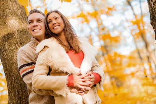 Beautiful lovely couple enjoying in sunny forest in autumn colors.