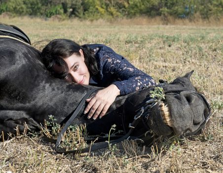 young girl riding a black stallion in a field