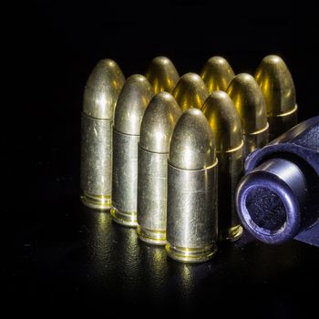 Black gun and bullets on a black background.