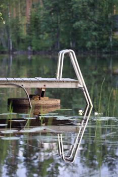Small wooden pier with stairs on calm lake, Finland