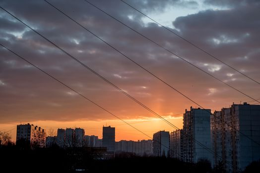 Dramatic Golden Sky Sunset in Summer. Houses at sunset.Beautiful colorful sunset under the city in the evening without any effects. Sky consist of many rainbow colors: red, orange, yellow, blue, violet.