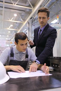 Men working with documents at plant near CNC machines