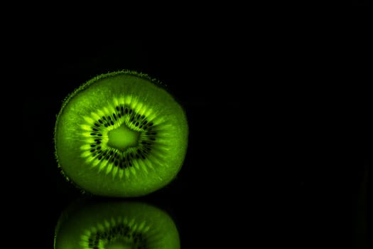 A slice of a kiwi in a black background