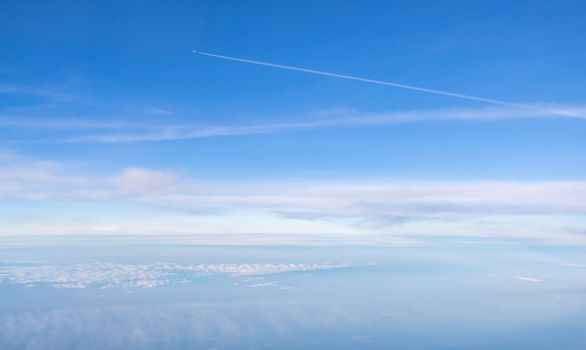 Small plane in the blue, boundless sky above white clouds