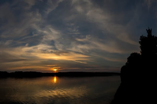 Majestic sunset on the river bank and its reflection in water