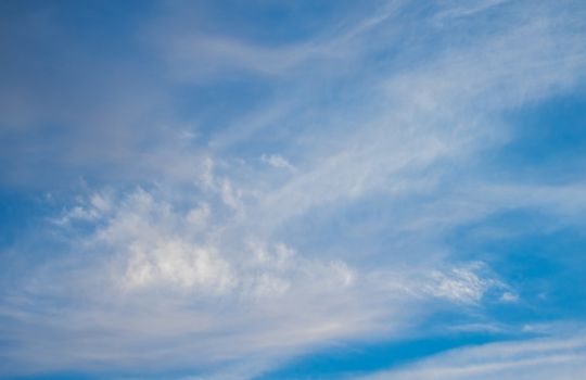 Blue boundless sky with the fluffy white clouds