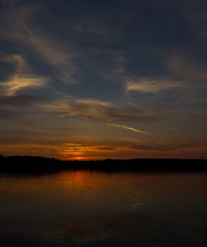 Majestic red sunset on the river bank and its reflection in water