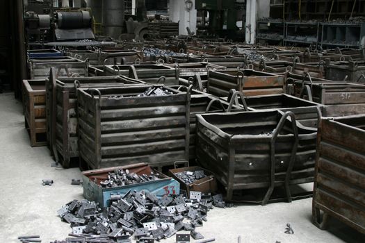 Large metal boxes containing metal pieces. Inside of a factory, industrial scene.  